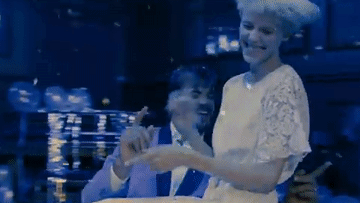 Animated GIF of a wheelchair-using man spinning around on the dance floor, an attractive woman on his lap